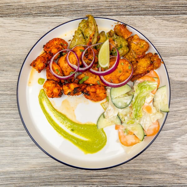 Indian chicken tikka, green chicken, and shrimp with red onion, lime, and salad.