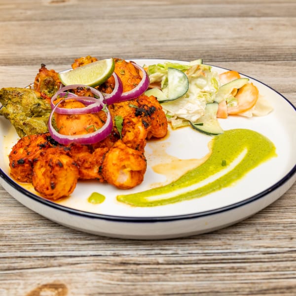 Magic Pepper's Indian dish with red and green spiced chicken, salad, lime, and green sauce.