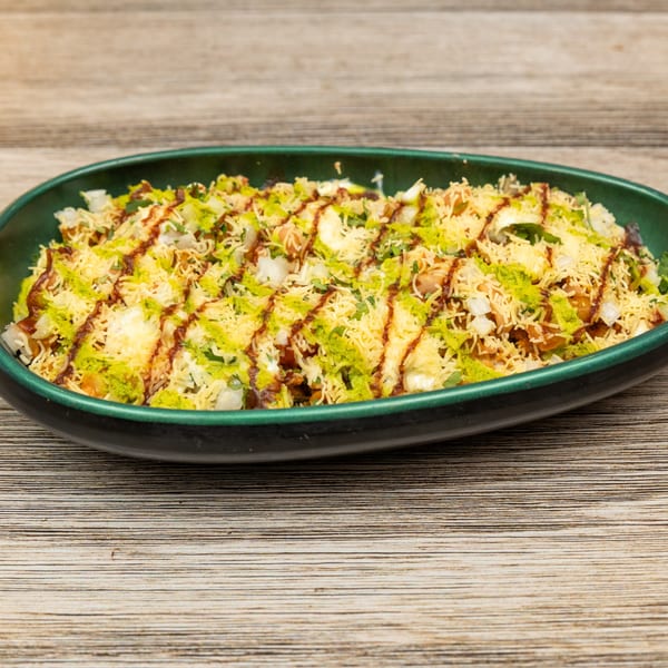 Magic Pepper's Indian Bhel Puri, a savory snack with puffed rice, vegetables, and chutneys, in a green bowl.