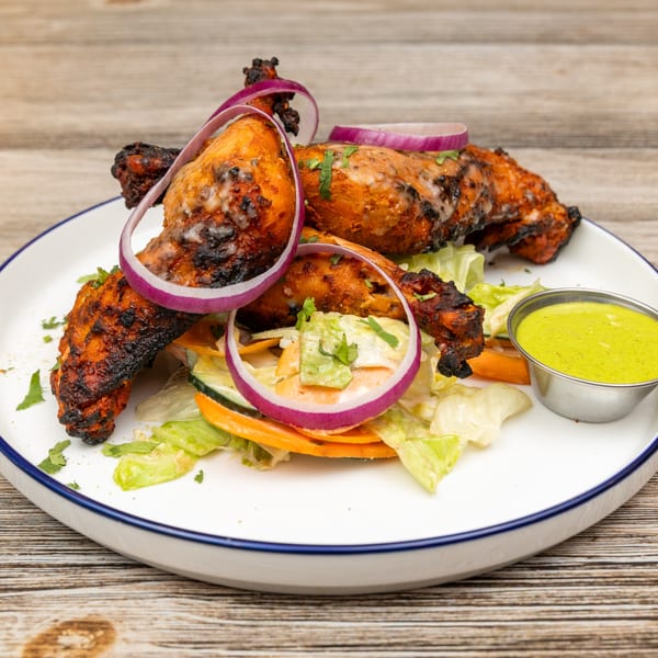 Magic Pepper's Indian tandoori chicken drumsticks with red onions, salad, and green chutney.