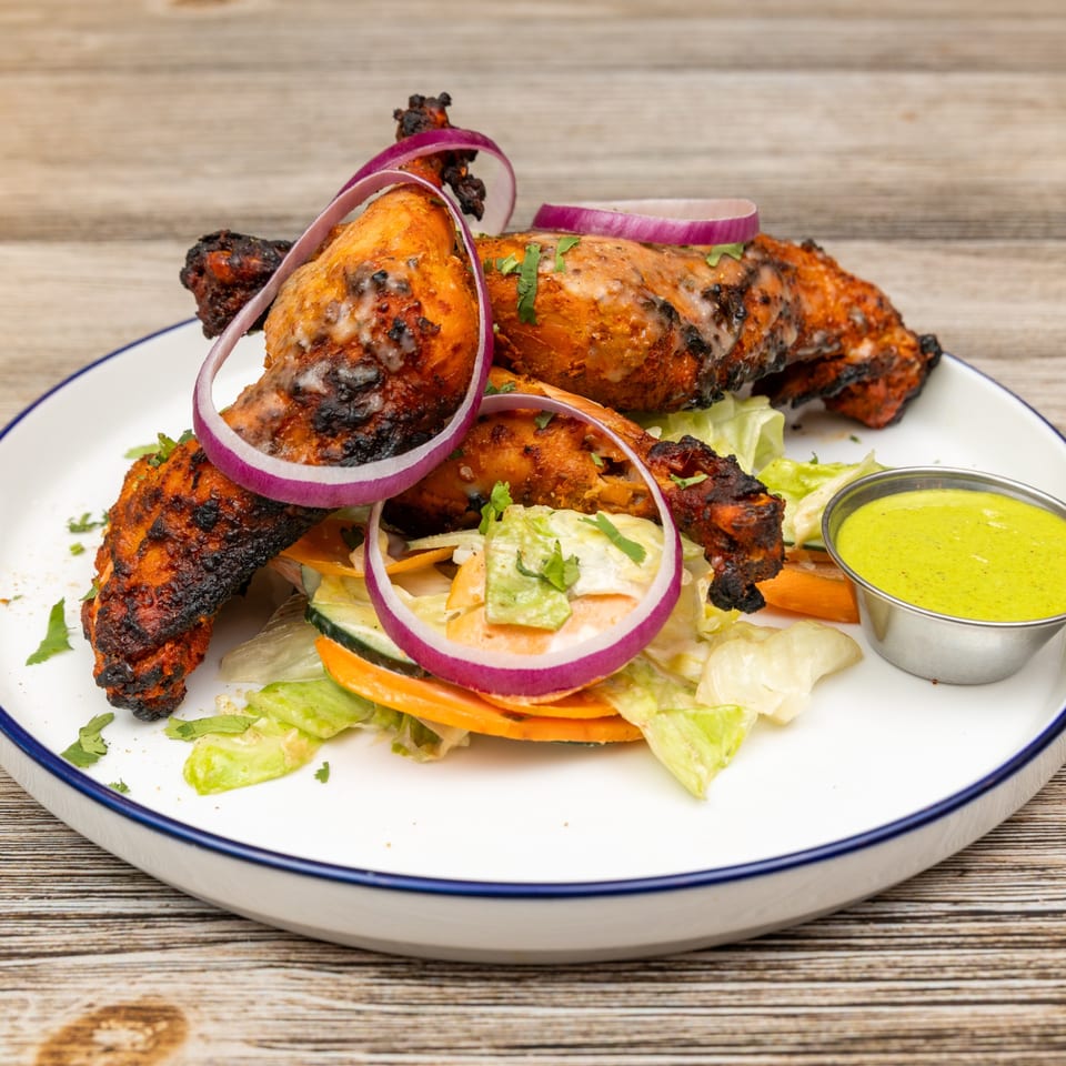 Magic Pepper's Indian tandoori chicken drumsticks with red onions, salad, and green chutney.